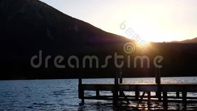 湖边的日落景象，木制的Jetty，轮廓山景